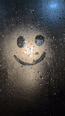 a smiley face drawn on a window with water drops