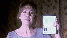 a woman is holding up a passport with a picture of a woman on it