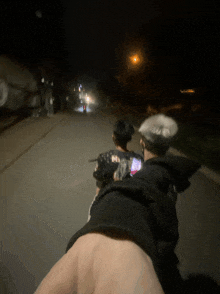 two people are walking down a street at night and one of them is wearing a shirt that says mi