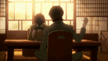 a man and a woman are sitting at a table in front of a window in a room .