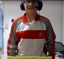 a man wearing headphones and a red white and grey shirt with a c on it