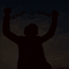 a silhouette of a man holding chains with the letter u written on them