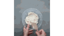 a person is mixing a dough in a bowl with a wooden spoon .