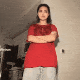 a woman in a red shirt stands with her arms crossed in a kitchen