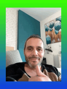 a man with a beard is giving a thumbs up in front of a painting