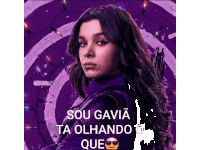 a woman in a purple suit is standing in front of a purple background with a gun .