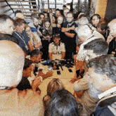 a man in a red bull shirt is surrounded by a crowd of people