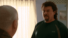 a bald man and a man with a mullet are looking at each other