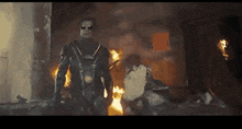 a man in a black suit and sunglasses stands in front of a fire