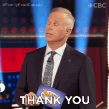 a man in a suit and tie is holding a thank you sign