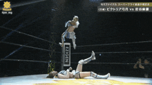 a woman in a wrestling ring is doing a flip over another woman in front of a sign that says gen