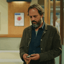 a man with a beard is holding a cell phone in his hands