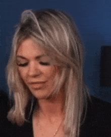 a close up of a woman 's face with blonde hair and a black jacket .