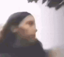a blurred image of a woman 's face with a few trees in the background