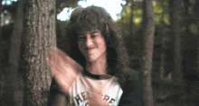 a girl with curly hair wearing a shirt that says " where peace "