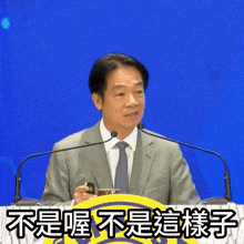 a man in a suit and tie stands at a podium with chinese writing on the bottom