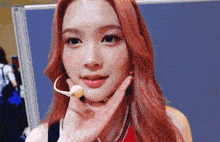 a woman with red hair is wearing a microphone on her neck