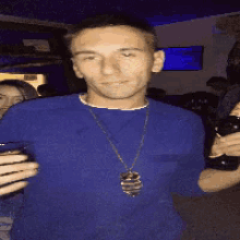 a man in a blue shirt is holding a glass and a bottle of beer
