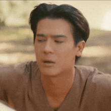 a close up of a man 's face with a brown shirt on