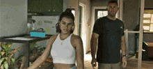 a woman in a white tank top stands next to a man in a black shirt with the word puma on it