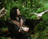 a man holding a bird in a jungle with a belt that says ' a ' on it