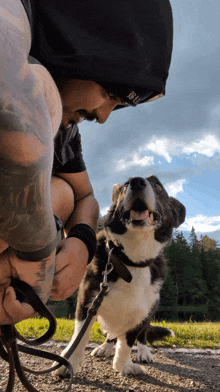 a man with a tattoo on his arm is kneeling down next to a dog on a leash