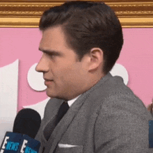 a man in a suit and tie is sitting in front of a microphone .