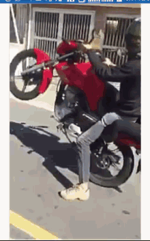 a man riding a red motorcycle on a street