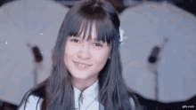 a young girl with long hair and a flower in her hair is smiling in front of a drum set .