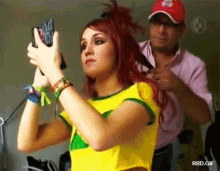 a woman with red hair is taking a picture of herself while a man holds her hair