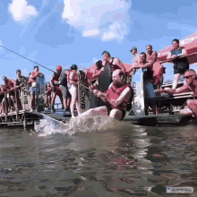 a man in a life jacket is sitting on a raft in the water with a group of people watching