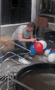 a man is kneeling down in a room with balloons
