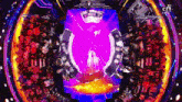 a group of people are sitting in front of a stage with a purple light coming out of it .