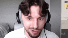 a man wearing headphones looks at the camera in front of a sign that says st ii