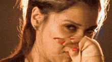 a woman is covering her face with her hand and looking at the camera .