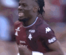 a close up of a soccer player wearing a maroon shirt with white letters on the sleeves .