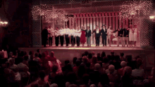 a group of people standing on a stage with a crowd watching