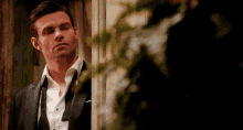 a man in a tuxedo and white shirt is standing in front of a door .