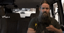 a man with a beard stands in front of a sign that says " you dumb "