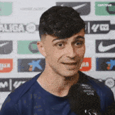 a young man is talking into a microphone in front of a nike logo .