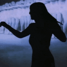a silhouette of a woman dancing in front of a row of white people