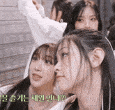 a group of girls are looking at each other with korean writing behind them