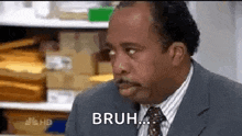 a man in a suit and tie is making a funny face while sitting at a desk .