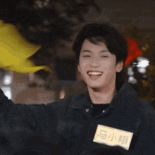 a young man wearing a name tag with chinese characters on it is smiling