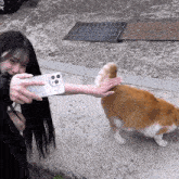 a woman taking a picture of a cat with a phone