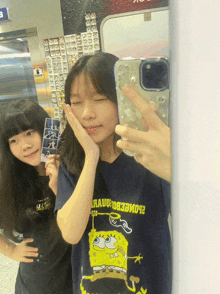 a girl wearing a spongebob shirt is taking a selfie with another girl