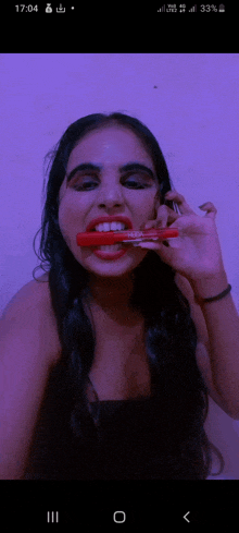 a woman is holding a red marker in her mouth with the time of 17:04