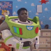 a man dressed as buzz lightyear from toy story is standing in front of a toy story wall .