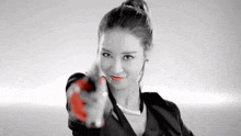 a woman in a black jacket is pointing a red object at the camera .