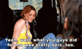 a woman in a yellow tank top is sitting in the back seat of a car talking to someone .